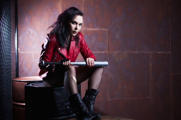istock Aggressive punk woman with a bat, in red leather jacket 688997312
