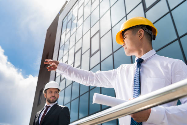 istock low angle view of professional architects in hard hats discussing project, successful businessmen concept 689003784