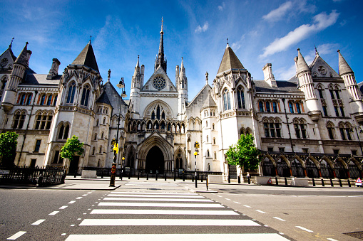 London, UK, May 2017, Exterior of the famous Royal Courts of Justice in London, viewed across the Strand with a zebra crossing in the foreground. It is the home of the High Court and the Court of Appeal and was designed by George Edmund Street who died before its completion.
