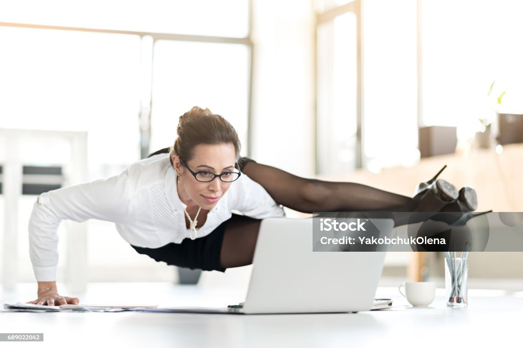 Happy woman doing exercises during working day Smiling assistant doing yoga in office. She tired of sitting. Flexibility concept Flexibility Stock Photo