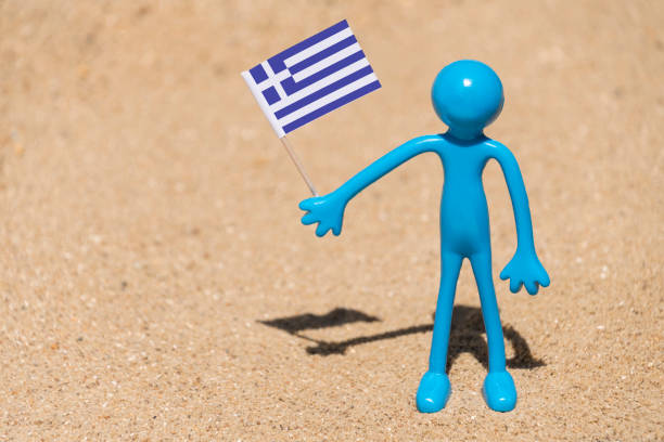 Man on a beach holding a Greek  flag