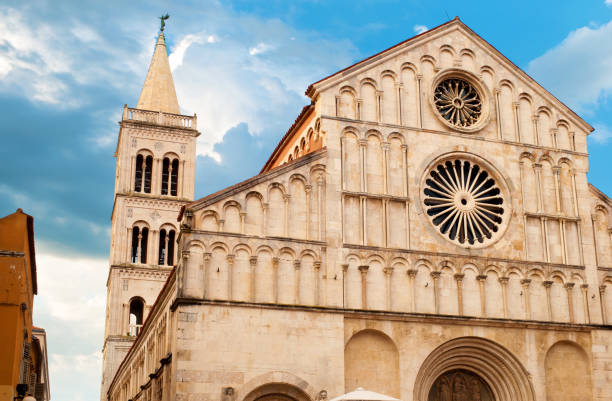 Architectural details of Saint Anastasia Cathedral and tower made of white stone on a summer morning. Dramatic cloudy sky. Zadar center, Croatia
