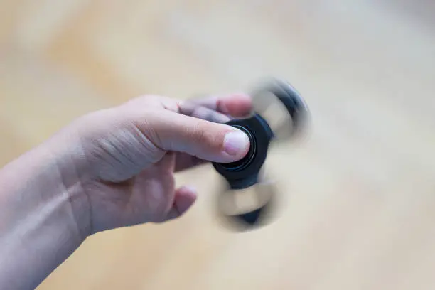 Photo of Young boy play with fidget spinner stress relieving toy