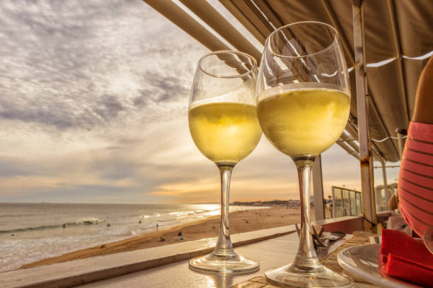 istock Glass of white wine overlooking the beach with sunset 689055432