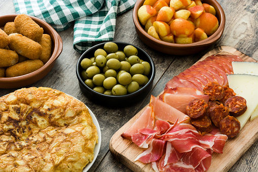 Traditional spanish tapas. Croquettes, olives,  ham and patatas bravas on wooden background