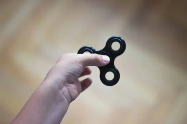 Photo of Young boy play with fidget spinner stress relieving toy