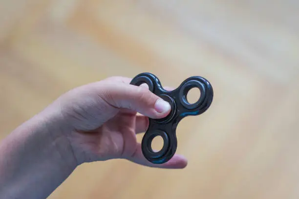 Photo of Young boy play with fidget spinner stress relieving toy
