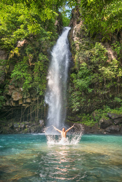 Handsome athletic man bathing in front of a beautiful Waterfall in the Rincón de la Vieja National Park in Costa Rica. Nikon D810. Converted from RAW.