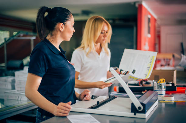 deux jeune femme travaillant dans une usine d’impression - print shop photos et images de collection