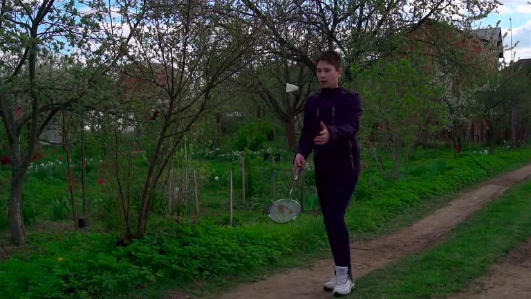 A young man plays with a racket and a shuttlecock in badminton. Slow-mo