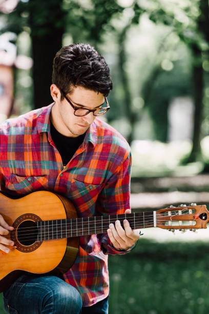 istock Man sitting and playing guitar in the park 689083342