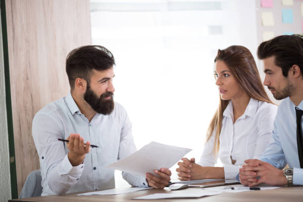 istock Team of three business people sitting at the table with several documents and discussing important questions 689087104