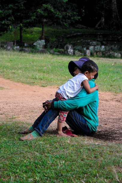 mother calming her son hugging him in the street during the day, Cambodia on November 4, 2014