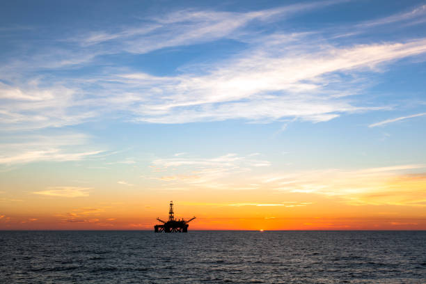 Silhouette of offshore oil platform at sunset stock photo