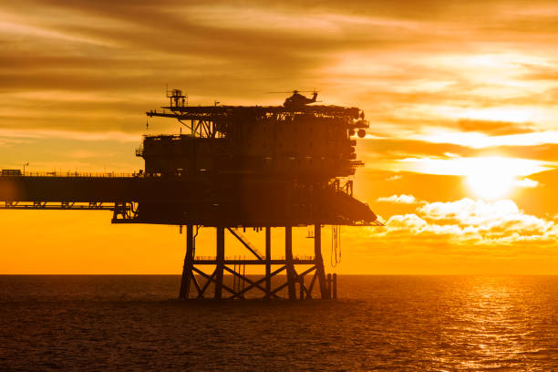 uma instalação offshore com um helicóptero aterrou em cima dele durante o tempo do sol - oil pumping unit at sunset time - fotografias e filmes do acervo