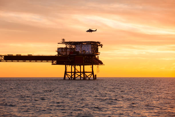 Helicopter is landing on an offshore oil installation during sunset stock photo