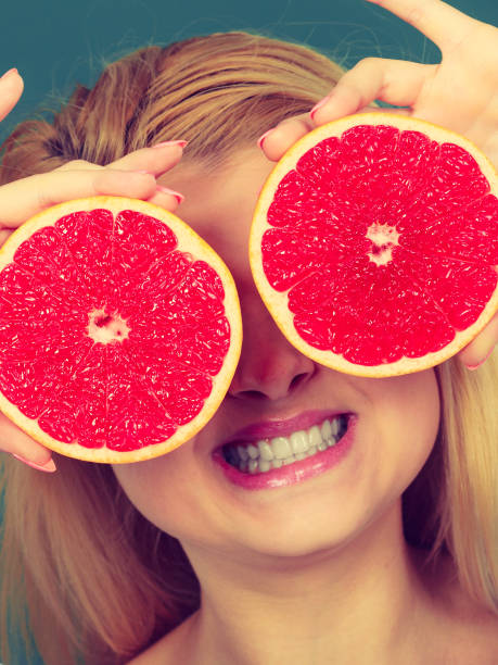 istock Woman holding fruit red grapefruit half on eyes 689134712