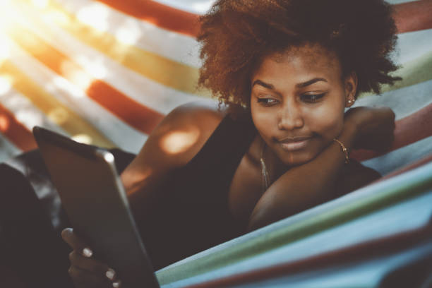 istock Attractive black cirly girl with digital tablet in hammock 689205512