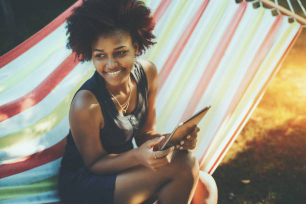 istock Mixed curly teenage female with digital tablet in hammock 689205624