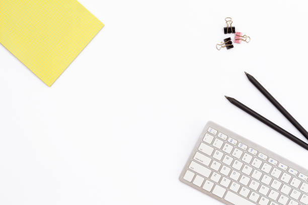 istock yellow Notepad, computer keyboard, two black pencil and clips for paper on white background. minimal concept of desktop in the office. 689216026