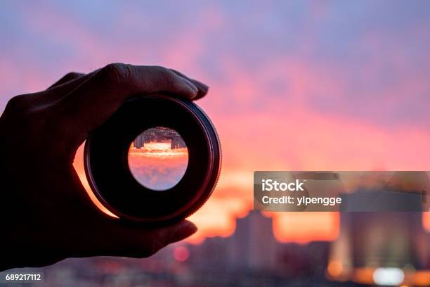 Hand Holding Camera Lens Looking At Scenics Of Glowing Clouds At Sunset Stock Photo - Download Image Now