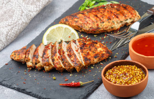 istock Chicken breast grilled with spices and sauce on the table. Dinner in a rustic style. Selective focus 689234128