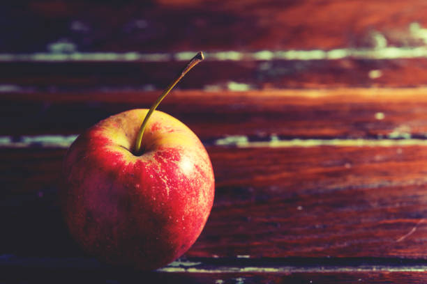 istock single red apple alone on wooden background 689241942