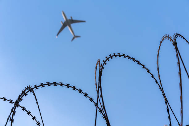 istock airplane flying over barbed wire around airport 689243522