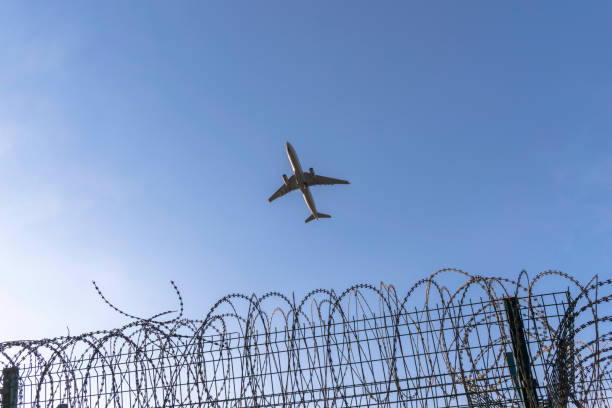 istock airplane flying over barbed wire around airport 689245614