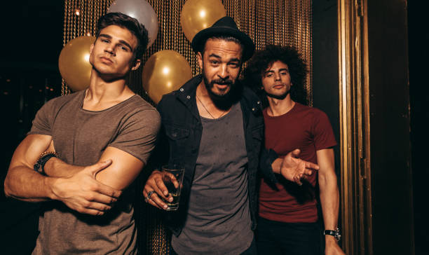Portrait of three young men standing in a nightclub. Stylish group of men at pub.