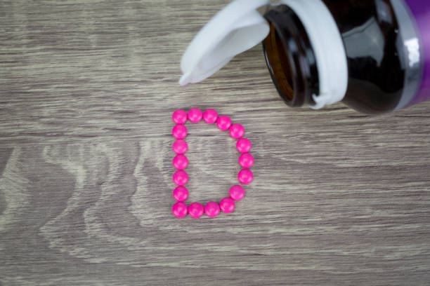 istock Pink pills forming shape to D alphabet on wood background 689271406
