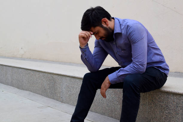 Stressed and sad young man sitting outside stock photo