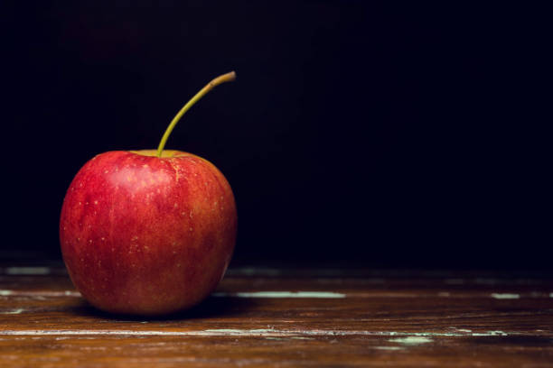 istock single red apple alone on wooden background 689285158