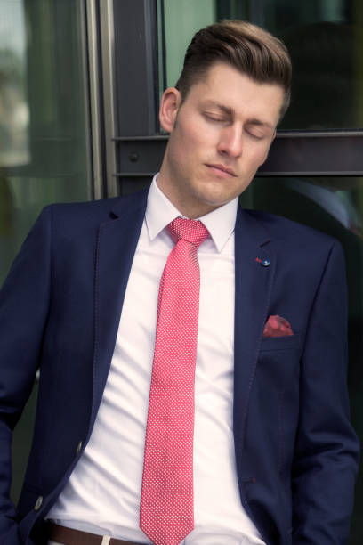 istock handsome man in suit leaning against window and sleeping 689316312