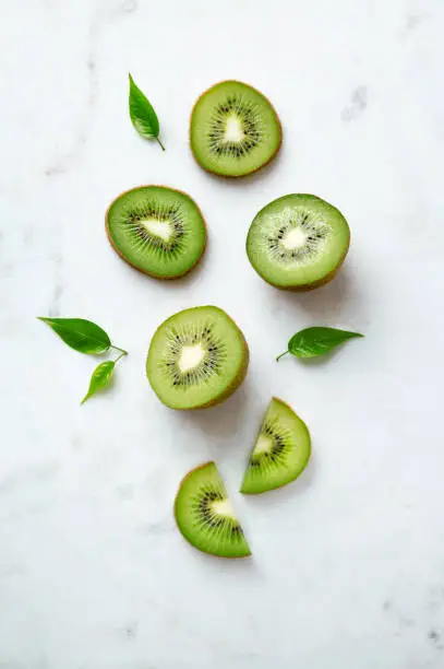 Kiwis flat lay on a marble background. Group of sliced and whole kiwi fruits viewed from above. Top view