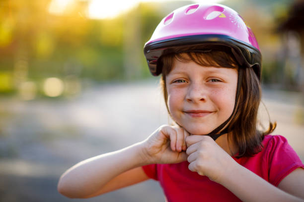 felice ragazza carina mettendo casco da ciclo su - sports helmet foto e immagini stock