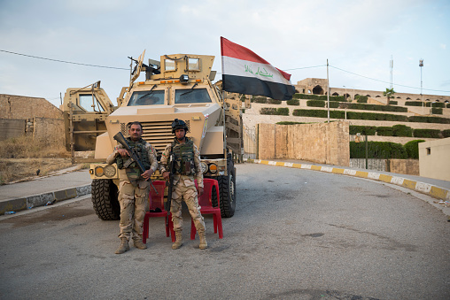 In the Iraqi city of Mosul, two Iraqi soldiers stand outside an Mine-Resistant Ambush Protected (MRAP) vehicle parked at the entrance to the shrine of Nabi Yunus, which was destroyed by ISIS in 2014.