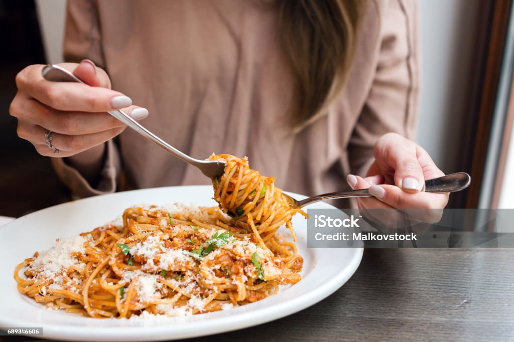 Mädchen isst italienischen Pasta mit Tomaten, Fleisch. Close-up Spaghetti Bolognese wickeln Sie es um eine Gabel mit einem Löffel. Parmesan-Käse - Lizenzfrei Nudeln Stock-Foto
