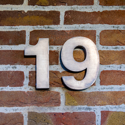 three dimensional metal house number nineteen on a brick wall