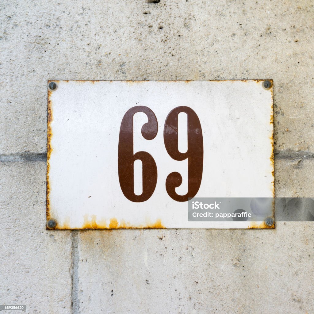 Number 69 enameled house number on a wall of natural stone House Address Stock Photo