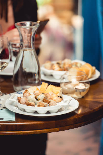 istock Snails with herbs butter, in traditional ceramic pan bread and sauce on a rustic wooden table. Top view 689366258