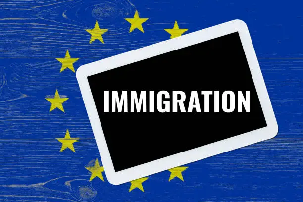 immigration, text on tablet pc over eu flag painted wooden planks