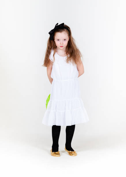 child little girl tries to put on her shoes isolated on white background