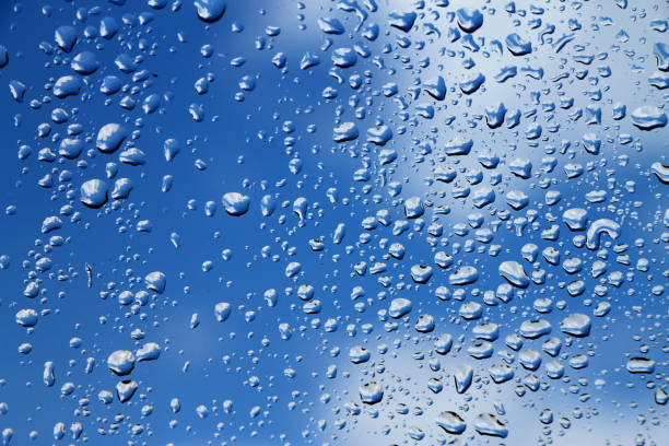 istock Rain drops on window with blue cloudy sky in background , spring rainy day 689404356