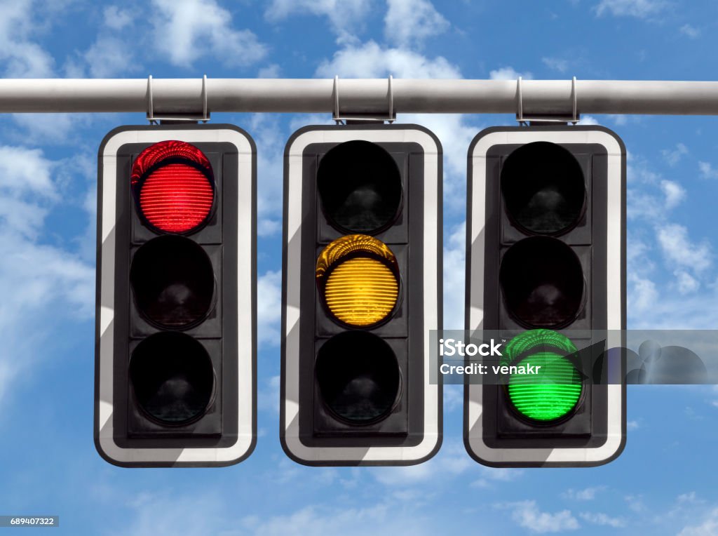 Traffic lights - red yellow green against sky Three traffic lights against blue sky background Stoplight Stock Photo