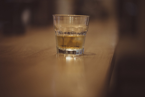 Glass of Whiskey on Dark Wood Bar counter, no people.