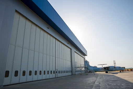 Airport hangar from the outside with big tall doors. Bright blue sky.