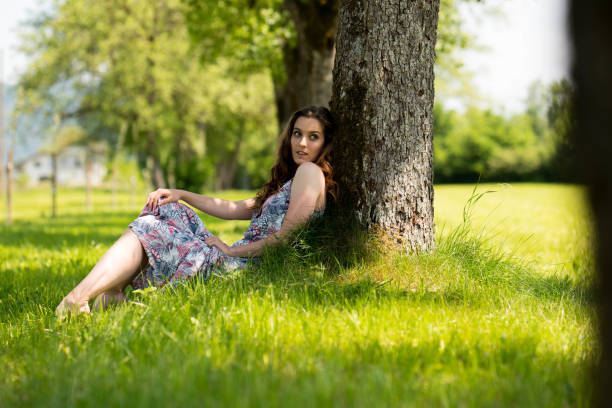 istock Woman sitting by the tree in green nature 689449596