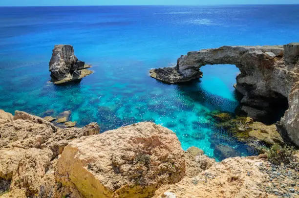 Photo of Beautiful natural rock arch near of Ayia Napa, Cavo Greco and Protaras on Cyprus island, Mediterranean Sea. Legendary bridge lovers.