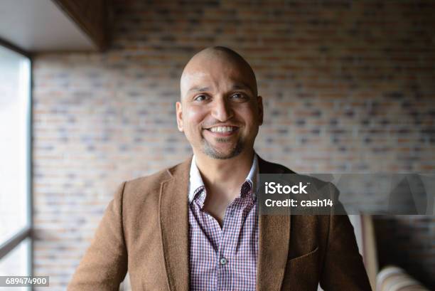 Portrait Of Happy Handsome Indian Business Man Smiling Confident And Friendly Indoors Stock Photo - Download Image Now